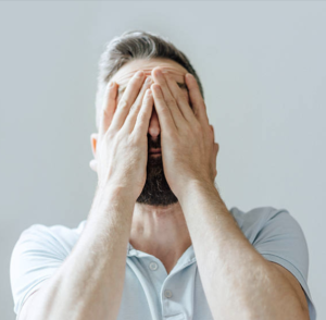 A person with their hands on their face, showing a deep sense of regret and distress after experiencing an emotional trigger. Their body language reflects the weight of their emotions